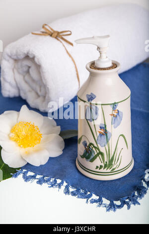 Lotion in an attractive pottery container, surrounded by a White Rugosa Rose and a bath towel Stock Photo