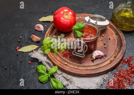 Glass jar with homemade classic spicy tomato pasta or pizza sauce. Italian healthy food on black  background. Stock Photo