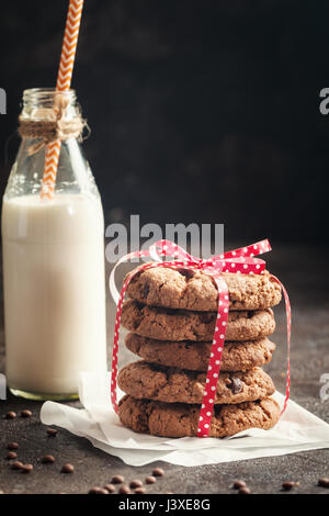 freshly baked chocolate chip cookies with milk on rustic background Stock Photo