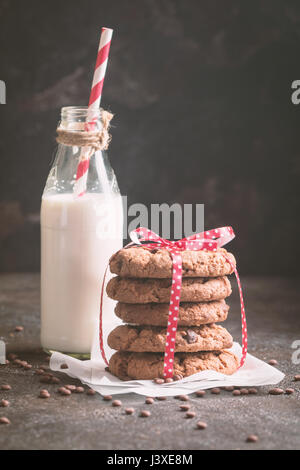 freshly baked chocolate chip cookies with milk on rustic background Stock Photo