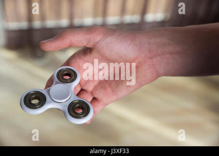 Young boy playing with fidget spinner toy to relieve stress at home Stock Photo