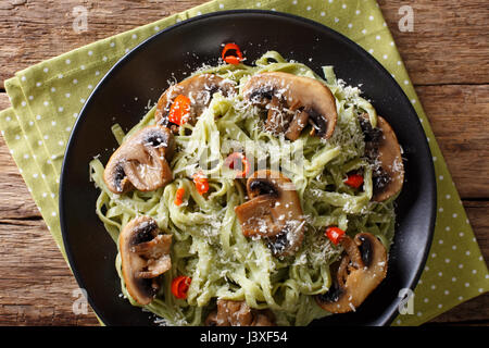 Spinach pasta with fried mushrooms and Parmesan cheese close-up on a plate. horizontal view from above Stock Photo