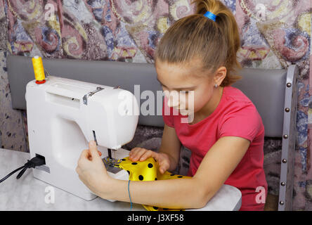 Girl learns to sew on an electric sewing machine Stock Photo
