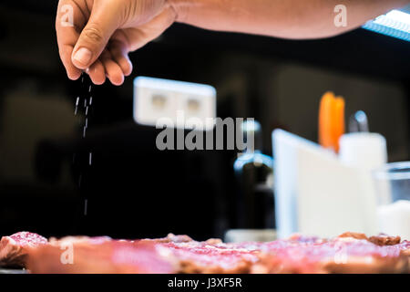 Chef's hands to season beef tenderloin, with background slightly blurred Stock Photo