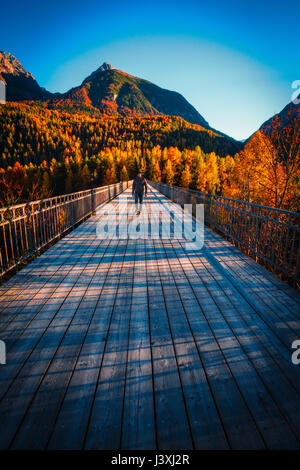 Man walking across wooden bridge, Scuol, Engadin,  Switzerland Stock Photo