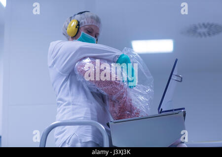 Worker pouring tablets into sorting machine  in pharmaceutical plant Stock Photo