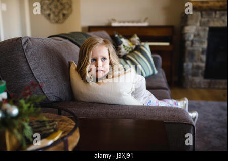 Fearful girl looking sideways from sofa Stock Photo