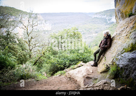 Woman leaning against rock looking away at view, Bruniquel, France Stock Photo
