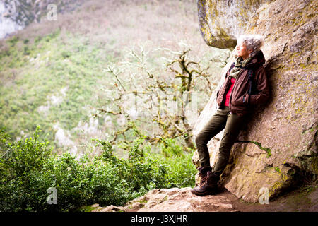 Woman leaning against rock looking away at view, Bruniquel, France Stock Photo