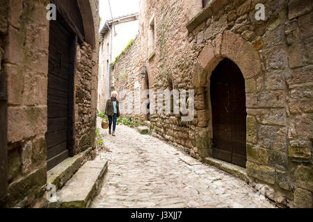 Woman walking in narrow rural street, Bruniquel, France Stock Photo