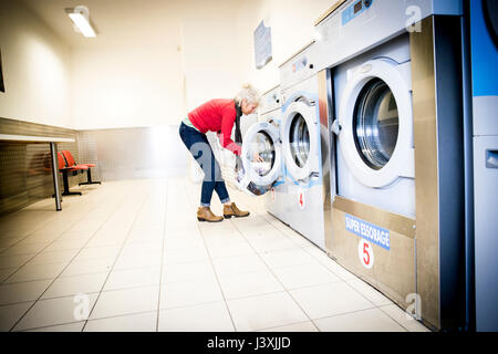 Woman using washing machine in laundrette Stock Photo