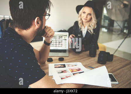 Photographer and stylist looking at photographs in photography studio Stock Photo