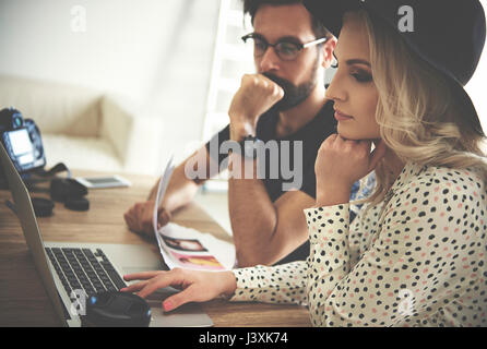Photographer and stylist looking at laptop in photography studio Stock Photo