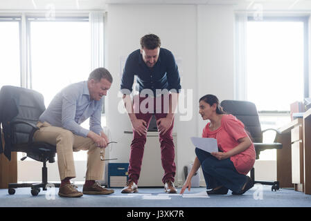Colleagues discussing papers on office floor Stock Photo