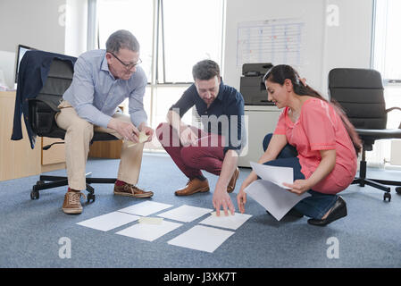 Colleagues discussing papers on office floor Stock Photo