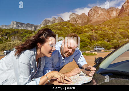 Couple leaning on car bonnet, looking at map, Cape town Stock Photo