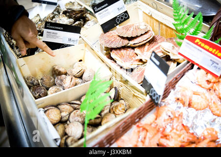 Hand pointing to shellfish display in supermarket, close-up Stock Photo