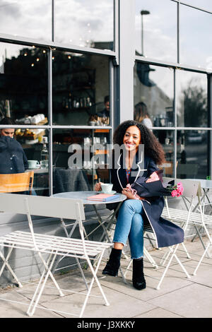 Mid adult woman having coffee at sidewalk cafe Stock Photo