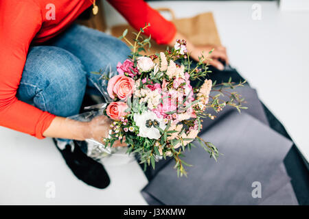 Neck down view of female florist wrapping flower bouquet in florists workshop Stock Photo