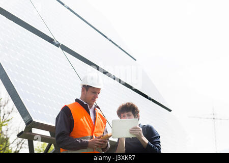Male and female engineers looking at digital tablet on solar panel site Stock Photo