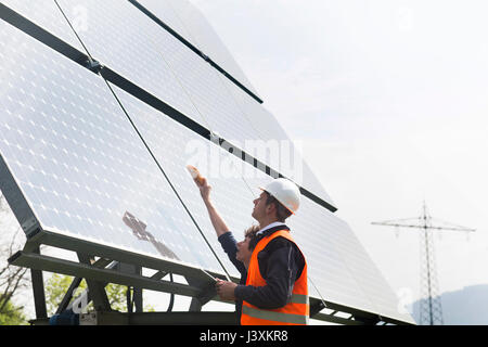 Male and female engineers using multimeter on solar panels Stock Photo