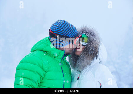 Mature couple kissing in falling snow, Gstaad, Switzerland Stock Photo