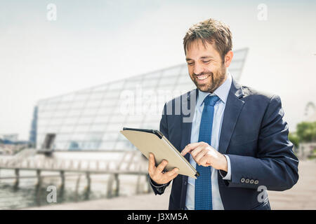 Businessman using digital tablet touchscreen on city waterfront Stock Photo