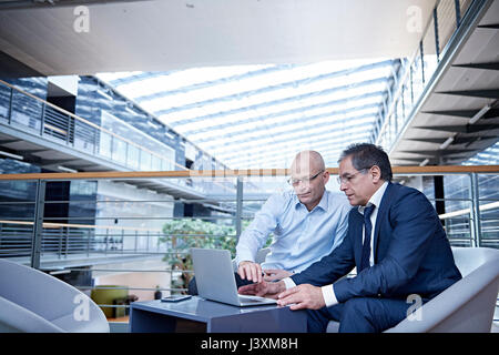 Two mature businessmen looking at laptop in meeting on office balcony Stock Photo