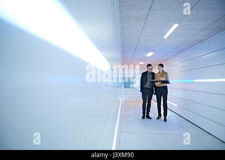 Businesswoman and man reading file in office corridor Stock Photo
