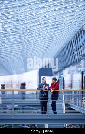 Businessman and woman talking in office atrium Stock Photo