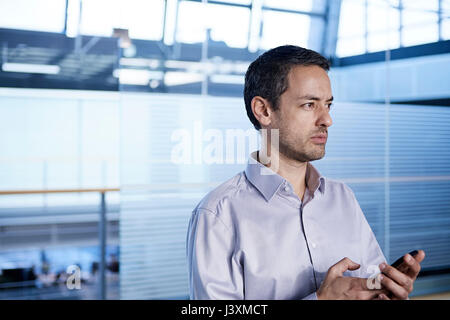 Businessman holding smartphone in office Stock Photo