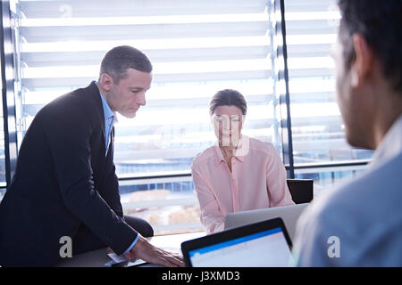 Businessmen and woman having meeting at office desk Stock Photo