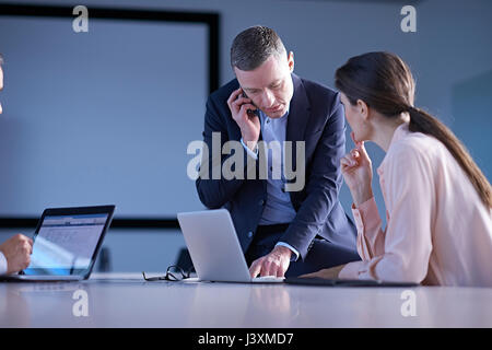 Business team making smartphone call and using laptop on office desk Stock Photo