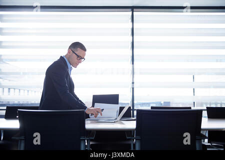 Businessman typing on laptop at boardroom table Stock Photo