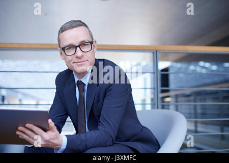 Portrait of confident businessman holding laptop on office balcony Stock Photo