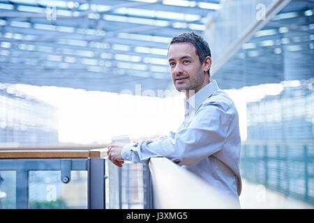 Businessman looking out from office balcony Stock Photo