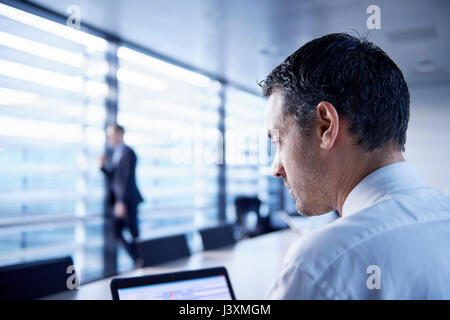 Businessman using laptop at boardroom table Stock Photo