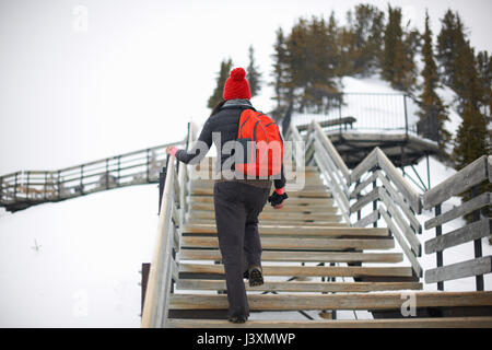Hiker ascending stairs on snow covered landscape, Banff, Canada Stock Photo