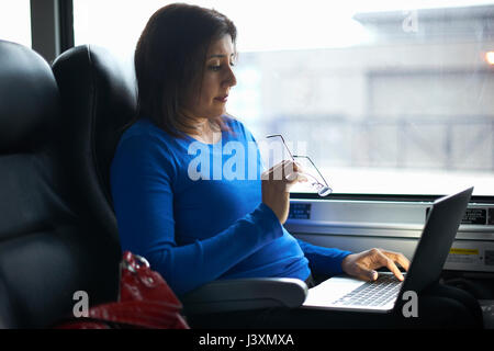 Woman travelling on train using laptop Stock Photo