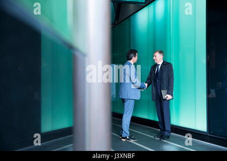 Businessmen shaking hands in modern glass building, London, UK Stock Photo