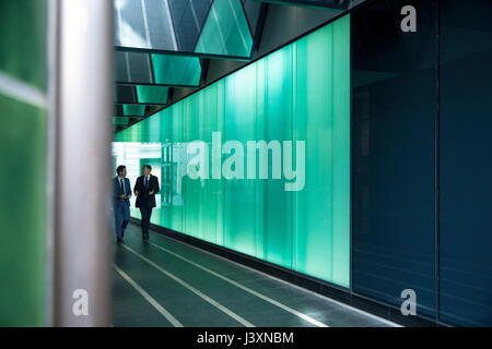 Businessmen walking through modern glass building, London, UK Stock Photo