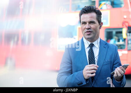 Businessmen in street with smartphone and earbuds, London, UK Stock Photo