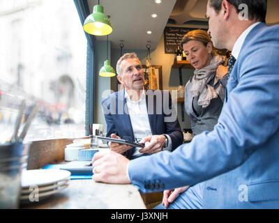 Businessmen and woman having discussion in restaurant window seat Stock Photo