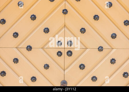 Yellow wooden door with iron ornaments. Close up Stock Photo