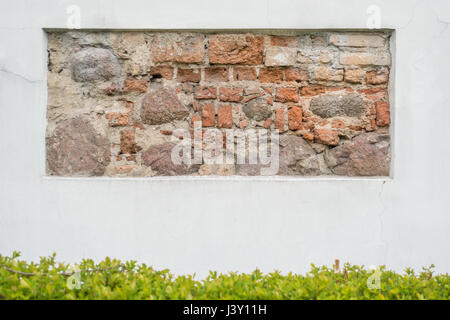 Old natural stone wall fragment in white plastered wall as background Stock Photo