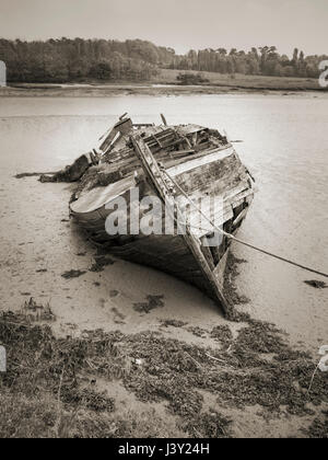 Derelict and rotting wooden boat have submerged in silt at low tide on ...