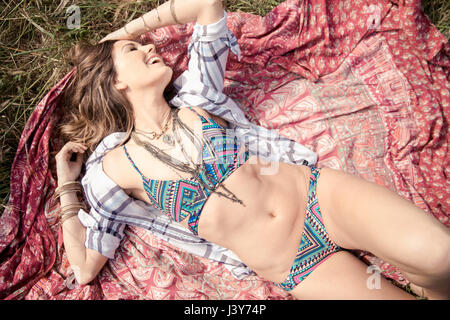 Boho style young woman in bikini lying on picnic blanket Stock Photo