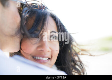 Over shoulder view of man kissing girlfriend on cheek Stock Photo
