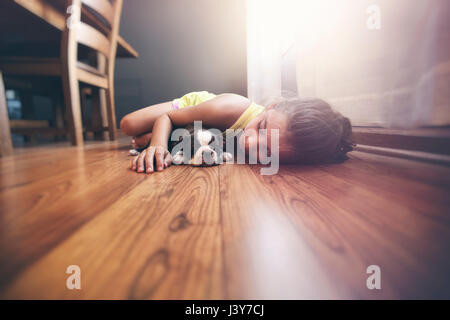 Girl lying on floor with sleeping Boston Terrier puppy Stock Photo