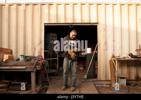 Builders in front of shipping container putting on protective gloves Stock Photo